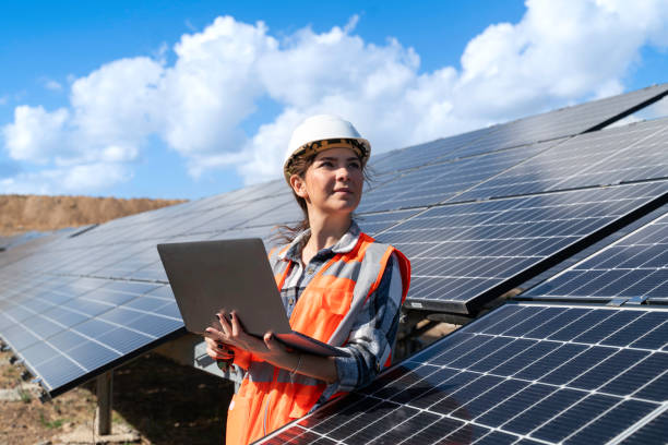 istock Young engineer inspect installation of solar panels installed check  with blueprint on the field, with recording inspection data on pc. 1830513300