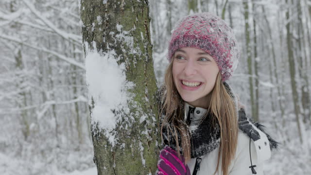 Teenager girl having a snowball fight in forest