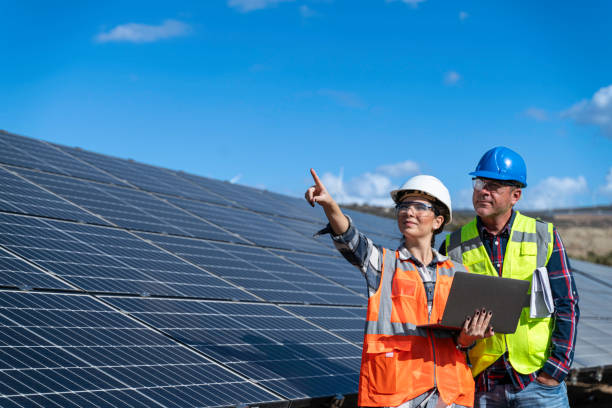 istock Young engineer inspect installation of solar panels installed check  with blueprint on the field, with recording inspection data on pc. 1830516120