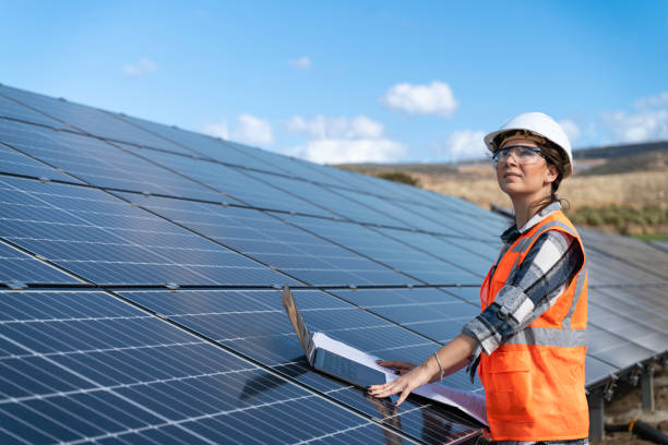 istock Young engineer inspect installation of solar panels installed check  with blueprint on the field, with recording inspection data on pc. 1830516121