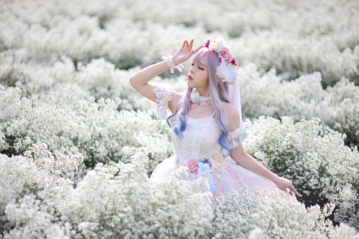 Beautiful young woman with white lolita dress with flowers garden Japanese fashion