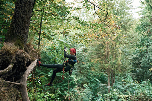 Climbing in the forest. Woman is in the forest using the safety equipment.