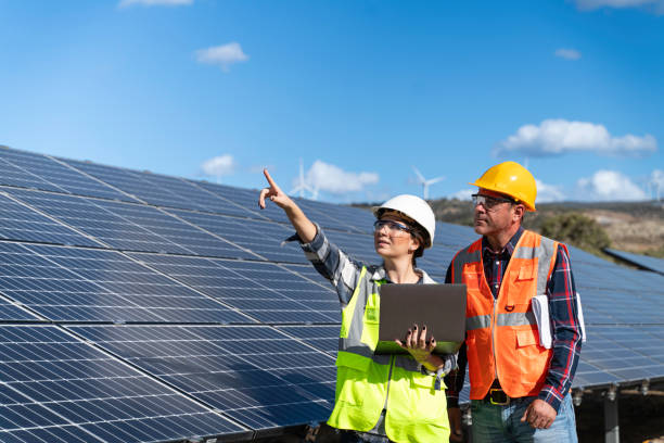istock Young engineer inspect installation of solar panels installed check  with blueprint on the field, with recording inspection data on pc. 1830522477