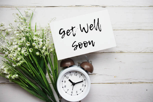 istock Get well Soon text message with alarm clock top view on wooden background 1830524650