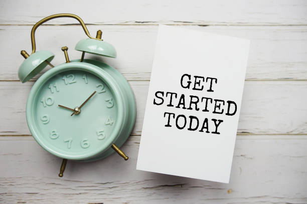 istock Get Started Today text message with alarm clock on wooden background 1830525189