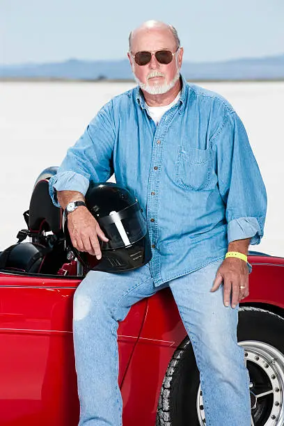 Portrait of a race car driver sitting on his red convertible coupe race car.