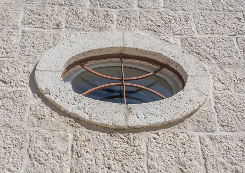 Round old window against the background of a stone wall.