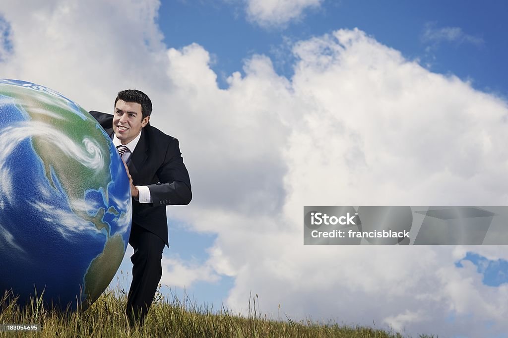 Moving the Earth A man pushing the earth (globe) in a field with open sky.Click on an Concepts Stock Photo