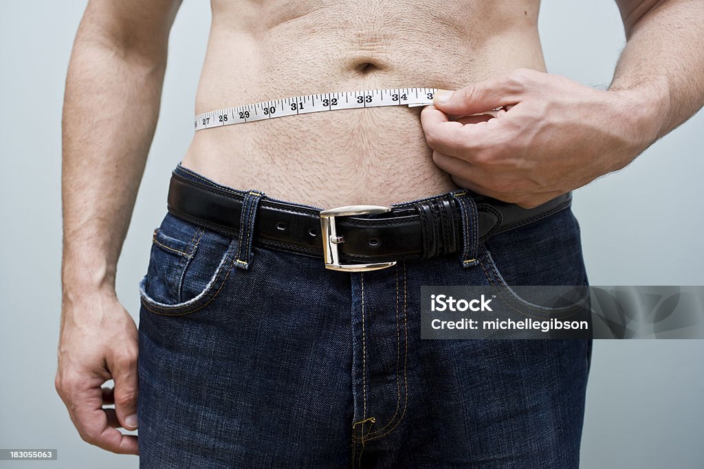 Waist Measurement Man takes a measurement of his stomach area with a measuring tape Loss Stock Photo