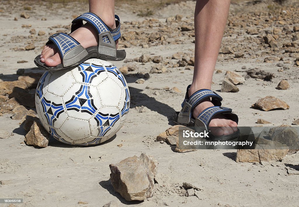 Soccer Rocks "A close up photo of a soccer ball in a rocky landscape, with an elementary aged boy in sandals." Sandal Stock Photo