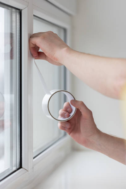 istock Man putting draught excluder tape on window, protection from the draft. 1830551183