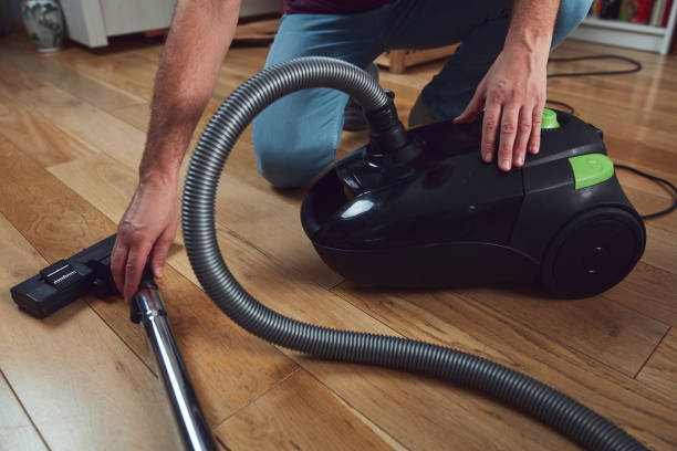 istock Man cleaning apartment with vacuum cleaner. 1830556055