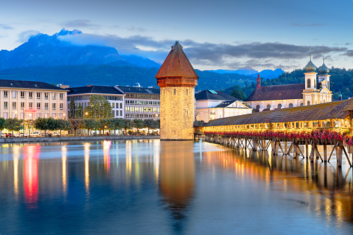 Lucerne, Switzerland with the Chapel Bridge over the River Reuss with Mt. Pilatus in the distance at dusk.