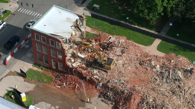Building demolition site of Historic Edwards Building in Berea, Kentucky. Hydraulic crusher excavator tearing down brick walls of old built structure