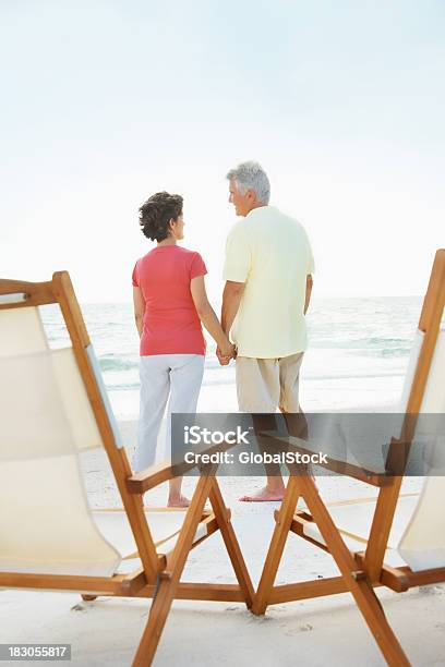Rear View Of Любящий Старший Пара Держаться За Руки На Пляж — стоковые фотографии и другие картинки 50-59 лет