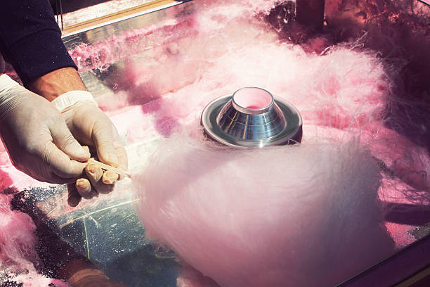 A person in latex gloves making pink cotton candy on a stick hands rolling filaments of pink sugar to make a cotton candy cone Cotton Candy stock pictures, royalty-free photos & images