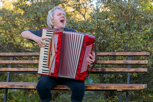 a cheerful woman plays the accordion and sings