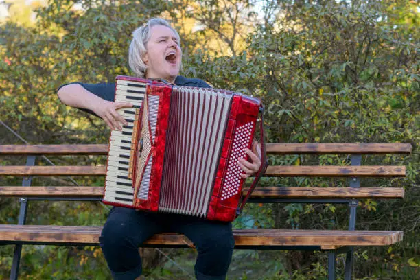 a cheerful woman plays the accordion and sings
