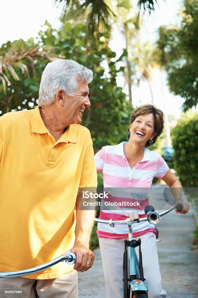 Felice coppia matura in bicicletta nel parco - Foto stock royalty-free di Abbigliamento casual