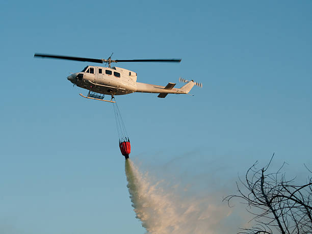 Helicopter drops water on fire from bucket - firefighting stock photo