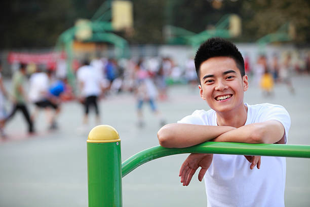 one happy college student looking at camera with people playing basketball in the background