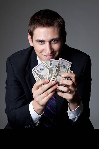 istock Smiling Man in Suit and Tie Holding Money 183057317