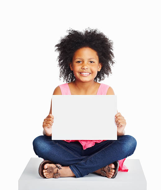 istock African kid sitting on cube as she holds a billboard 183057374