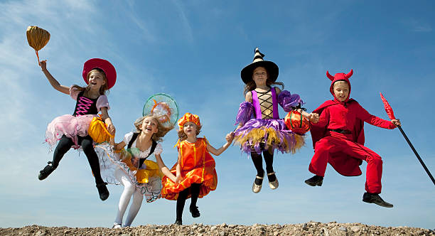 cinco halloween niños de salto en el cielo azul. - costume stage costume sunlight carnival fotografías e imágenes de stock