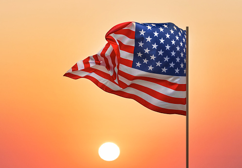 Flag of the United States. American flag against the backdrop of sunset or sunrise.