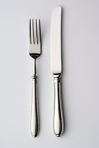 Overhead shot of knife and fork isolated on white background.