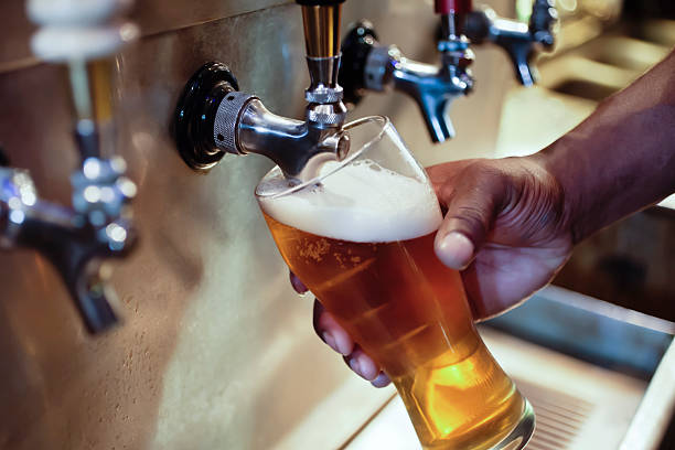 Bar Beer Tap with African American Person's Hand Filling Glass stock photo