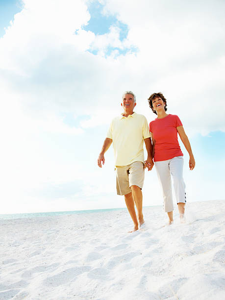 istock Mature couple holding hands while walking on beach 183059008