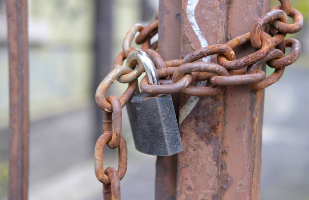 Close-up of a rusty and massive padlock on an iron chain against a blurred background