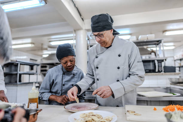 istock Chef and assistant preparing a plate in a commercial kitchen 1830611074