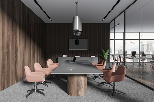 Stylish business interior with conference and coworking zone, pc computers on desk in row. Glass room with tv screen and panoramic window on skyscrapers. 3D rendering