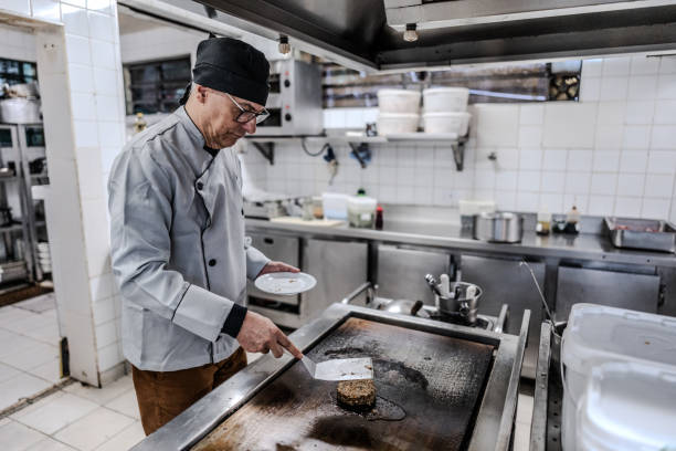 istock Senior chef preparing a hamburger in a commercial kitchen 1830612169