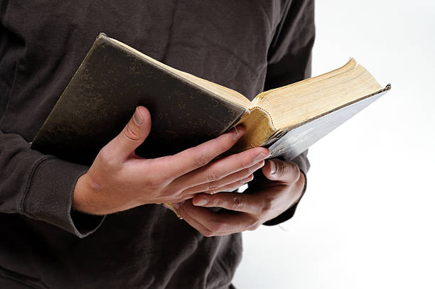 young man's hands holding a worn Bible stock photo