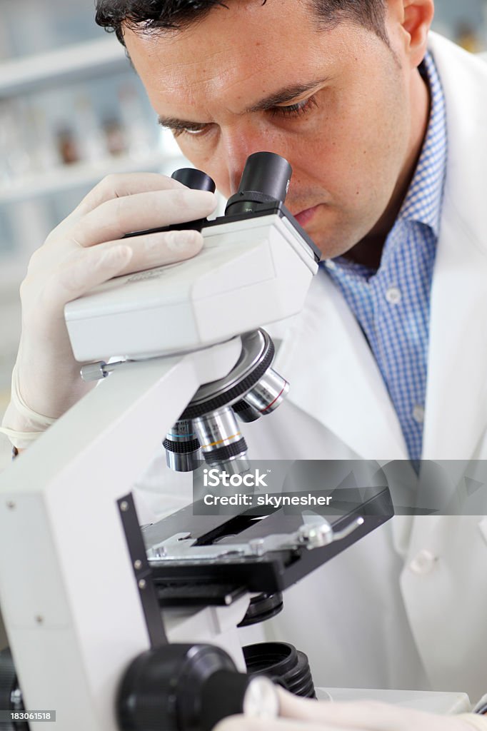 Scienziato ricercatore guardando in un microscopio in laboratorio. - Foto stock royalty-free di Adulto