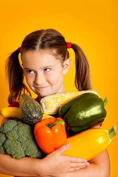 istock Young Girl Holding Vegetables, Bell Peppers, Broccoli, Squash, Zucchini, Corn 183061552