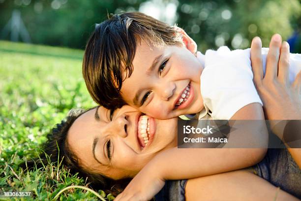 Sorridente Jovem Mãe E Filho Abraçar Ao Ar Livre - Fotografias de stock e mais imagens de Criança pequena - Criança pequena, Deitar, Relva