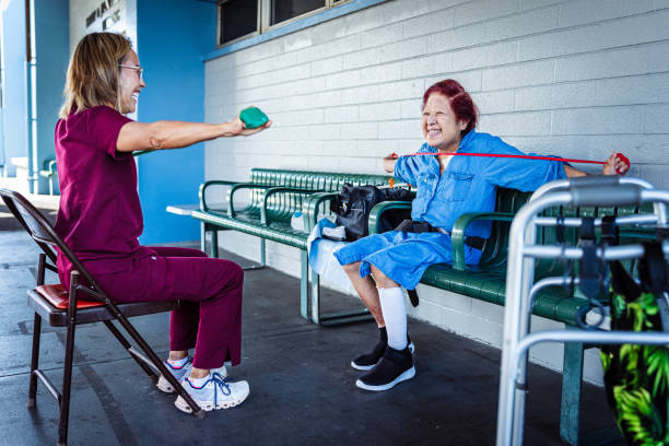 Cheerful elderly woman using resistance band during physical therapy appointment