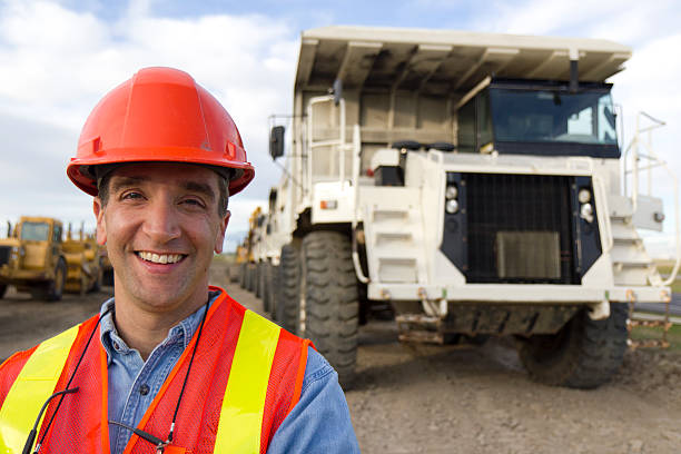 Heavy Equipment Driver Royalty free image of a construction worker in front of a massive dump truck.  This could be used for construction or oil industry. miner photos stock pictures, royalty-free photos & images