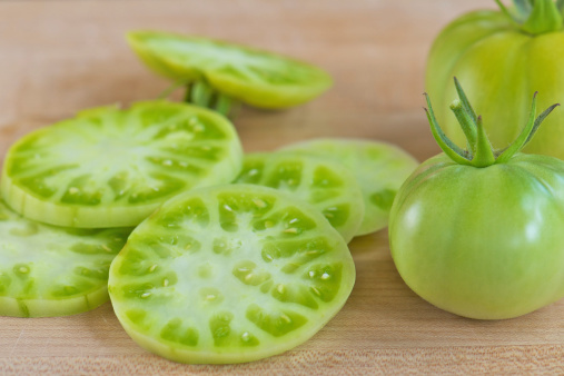 Sliced green tomatoes on wooden cutting board