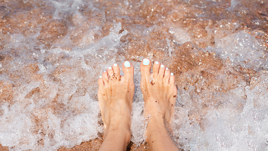 Woman's feet and sea wave. Vacation and travel concept. Close-up.