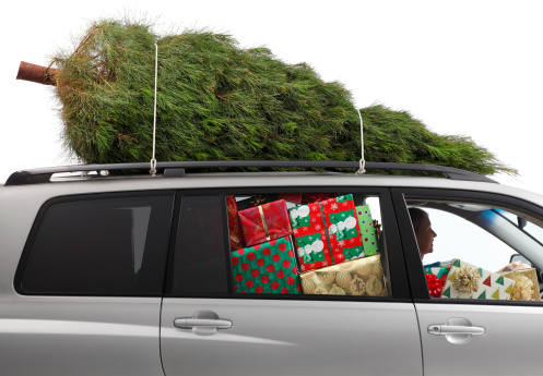 A woman driving a car filled with Christmas presents and a Christmas tree on top..To see more holiday images click on the link below:
