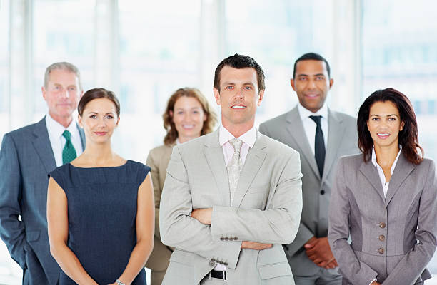istock Business man with hands folded and his team in background 183064762