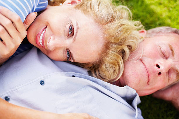 smiling mature female resting on senior man's chest - ogen dicht closeup vrouw 50 jaar stockfoto's en -beelden