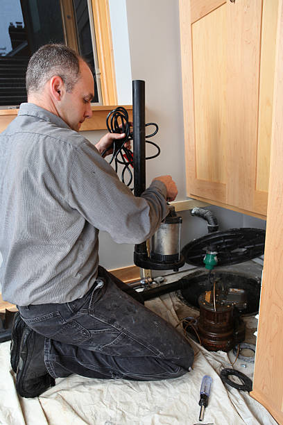 Plumber Installing Sump Pump Authentic photo of master plumber installing new sump pump. water pump stock pictures, royalty-free photos & images