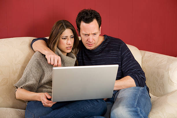 concerned couple browsing the web stock photo