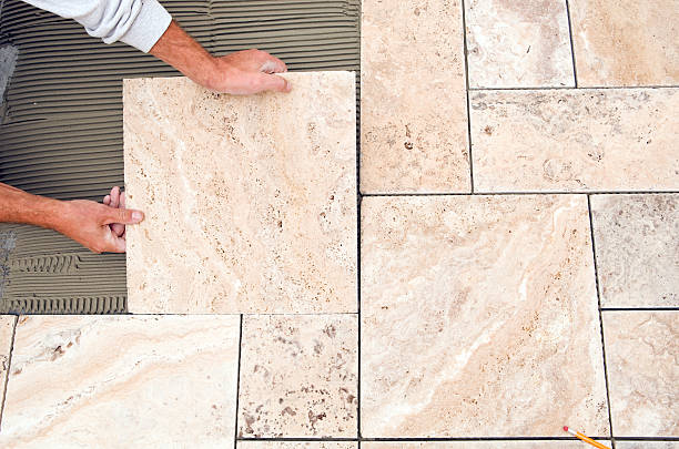 operaio luoghi nuove piastrelle su un pavimento del bagno - tile bathroom tiled floor marble foto e immagini stock
